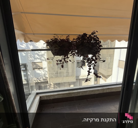 מרפסת עם סוכך כתום תלוי מעל עציצים
